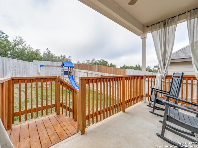 wooden terrace featuring a playground, a fenced backyard, and a lawn