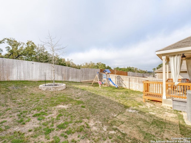 view of yard with a deck, a fenced backyard, and a playground