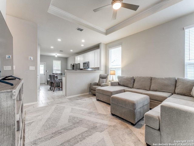 living room with light carpet, visible vents, crown molding, and a raised ceiling