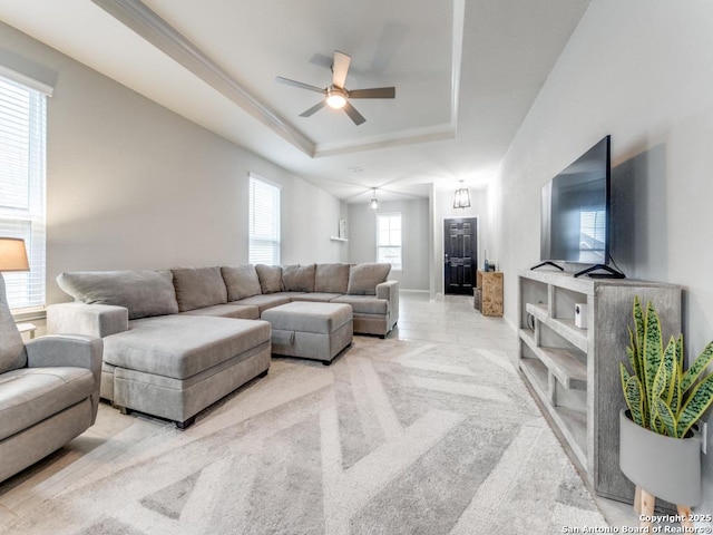 living room with a tray ceiling, ceiling fan, and crown molding