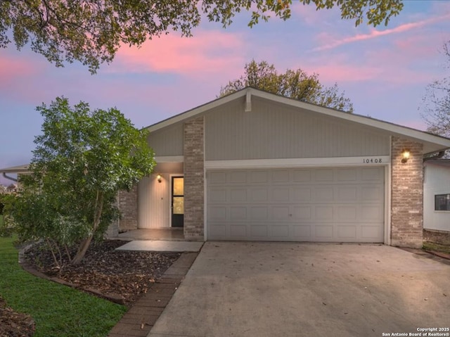 view of front of house with a garage, brick siding, and driveway