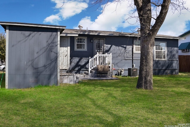 back of property featuring a yard and central AC