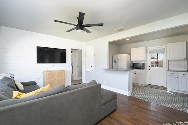 living area with ceiling fan, visible vents, baseboards, and dark wood-style floors