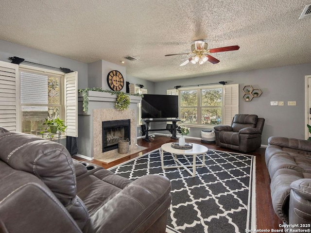 living area with visible vents, baseboards, wood finished floors, and a fireplace