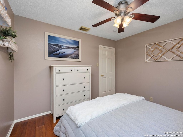 bedroom featuring visible vents, ceiling fan, baseboards, wood finished floors, and a textured ceiling