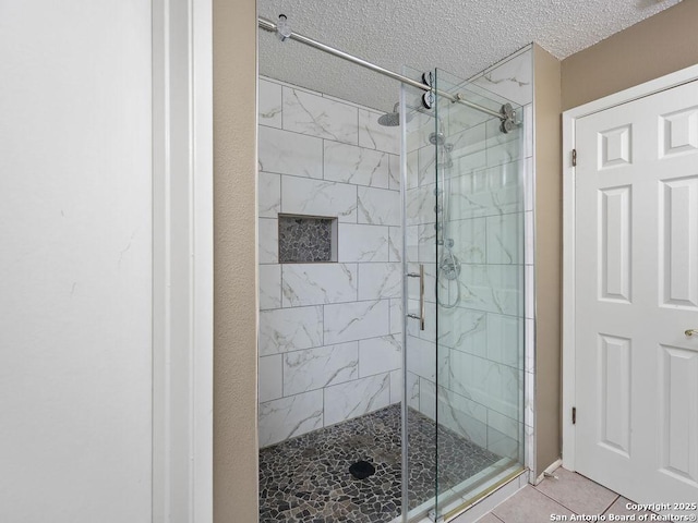 full bathroom with tile patterned floors, a textured ceiling, and a shower stall