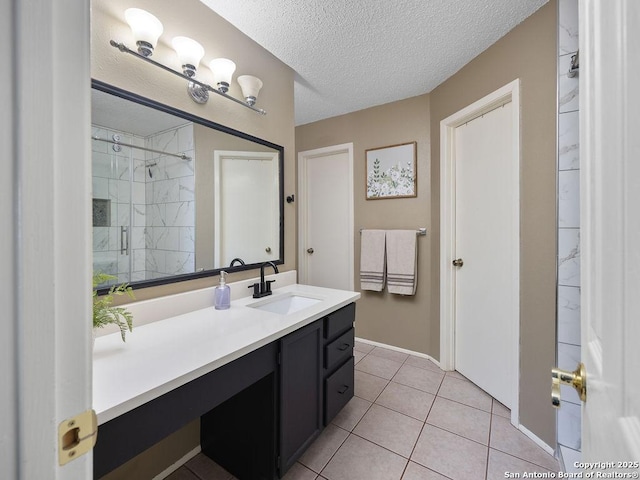 bathroom with tiled shower, a textured ceiling, vanity, and tile patterned flooring