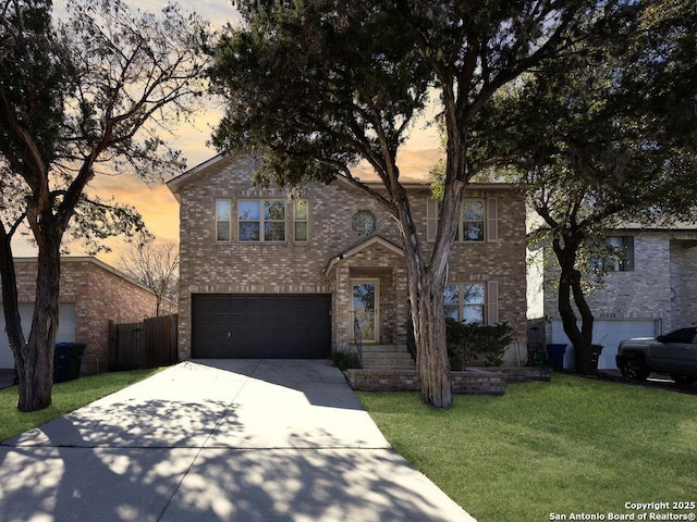 traditional home with a lawn, driveway, fence, an attached garage, and brick siding