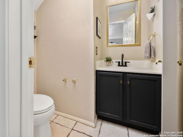 half bath featuring vanity, tile patterned floors, toilet, and baseboards