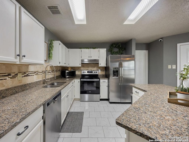 kitchen featuring visible vents, a sink, under cabinet range hood, stainless steel appliances, and a skylight