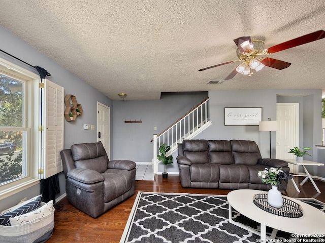 living room featuring visible vents, a textured ceiling, wood finished floors, and stairs