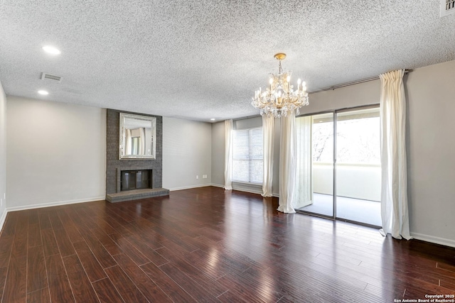 unfurnished living room featuring visible vents, a fireplace, an inviting chandelier, wood finished floors, and a textured ceiling