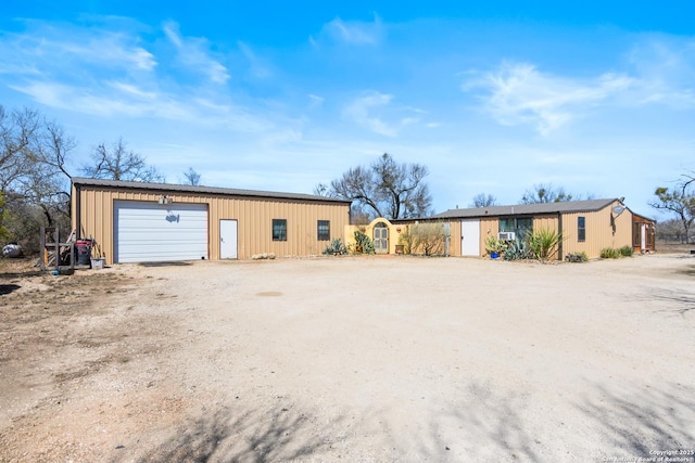 exterior space with dirt driveway, an outbuilding, and a detached garage