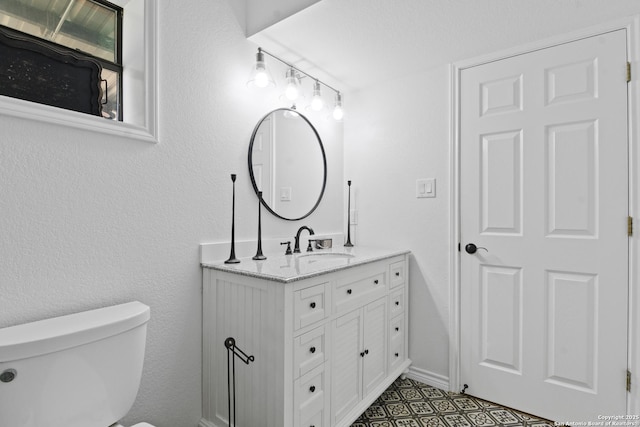 bathroom featuring toilet, vanity, and baseboards