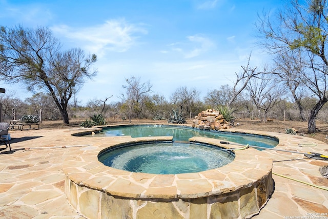 outdoor pool with an in ground hot tub and a patio area