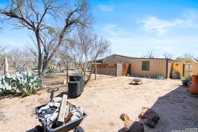 view of yard with an outbuilding, fence, and an outdoor fire pit