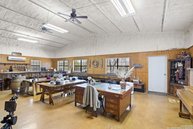 interior space featuring a wall mounted air conditioner, finished concrete flooring, and a ceiling fan