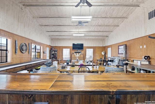 interior space featuring high vaulted ceiling, a healthy amount of sunlight, ceiling fan, and wood walls