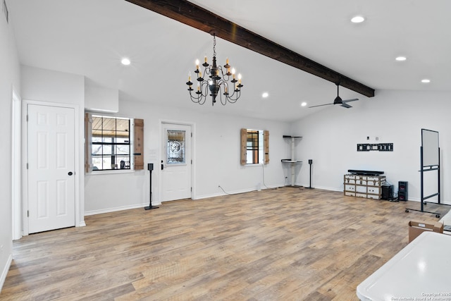 interior space featuring light wood-type flooring, ceiling fan with notable chandelier, a healthy amount of sunlight, and vaulted ceiling