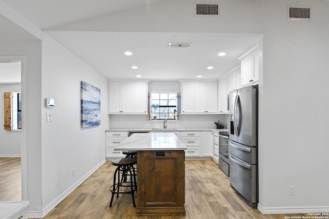 kitchen with decorative backsplash, visible vents, white cabinetry, and stainless steel appliances