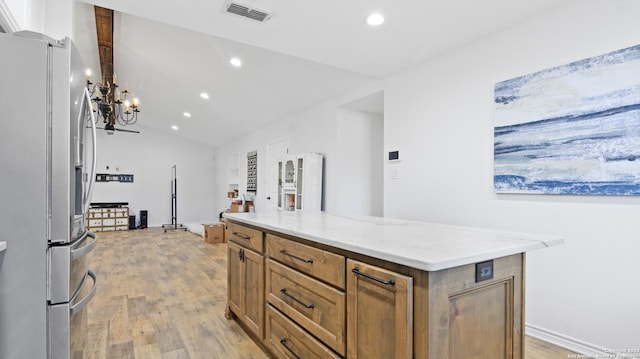 kitchen featuring light wood finished floors, visible vents, stainless steel fridge, and brown cabinetry