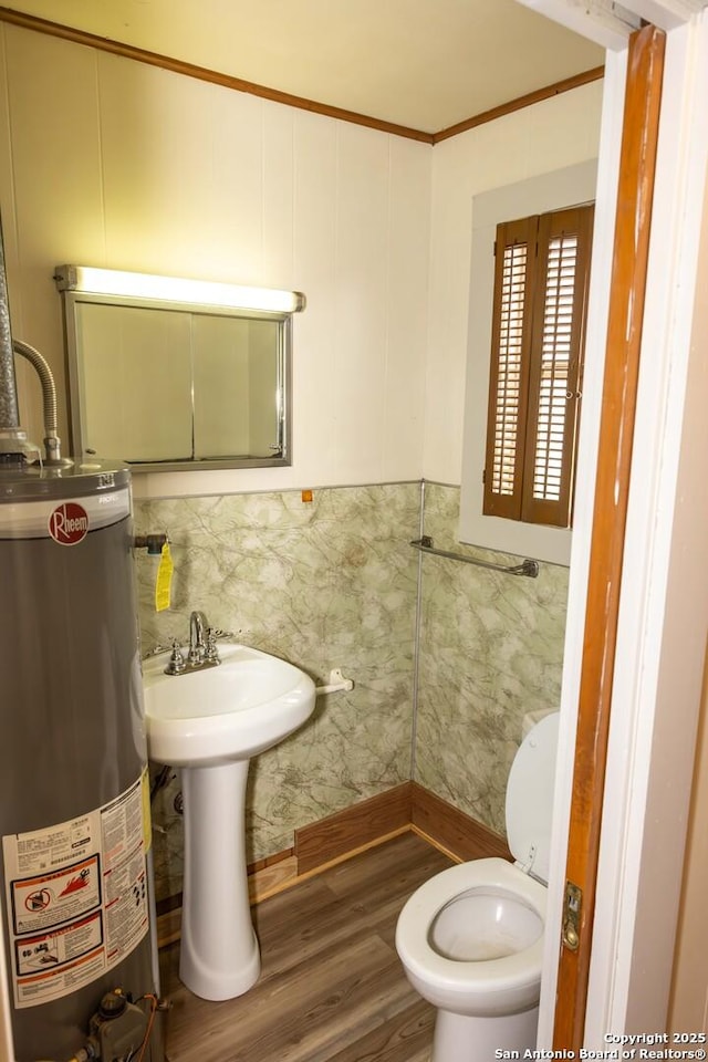 bathroom featuring toilet, ornamental molding, wood finished floors, water heater, and tile walls