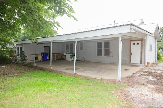 back of house with a patio, a lawn, and metal roof