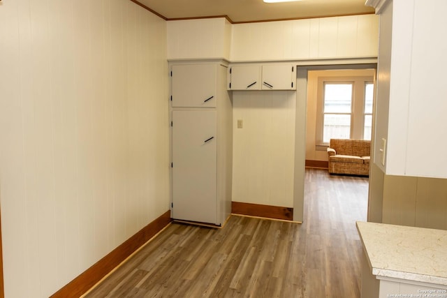 kitchen with light countertops, wood finished floors, baseboards, and ornamental molding