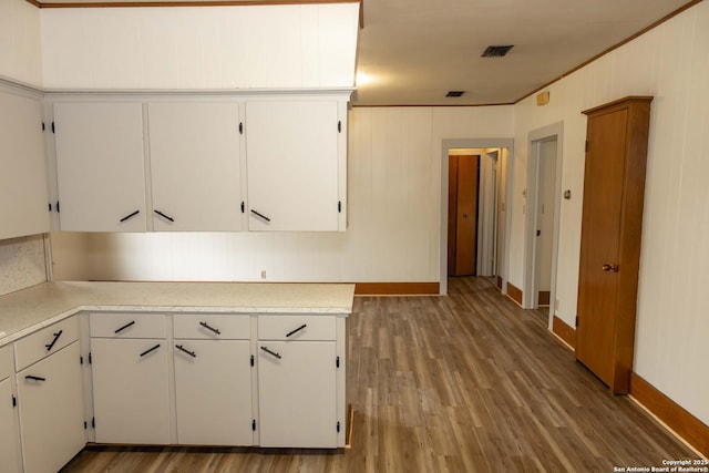 kitchen featuring light wood-type flooring, visible vents, white cabinetry, crown molding, and light countertops