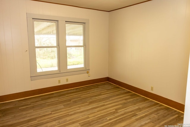 unfurnished room with baseboards, wood finished floors, and ornamental molding