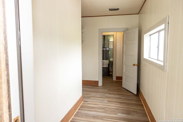 hall featuring visible vents, baseboards, light wood-style flooring, ornamental molding, and gas water heater