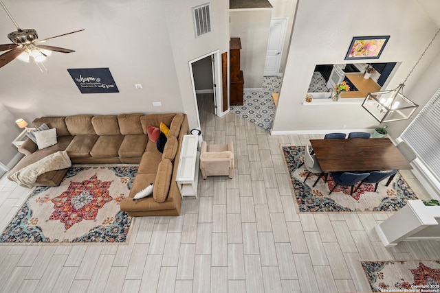 living area with visible vents, ceiling fan, baseboards, and wood finish floors