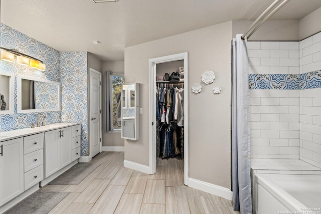 bathroom featuring a spacious closet, vanity, and baseboards