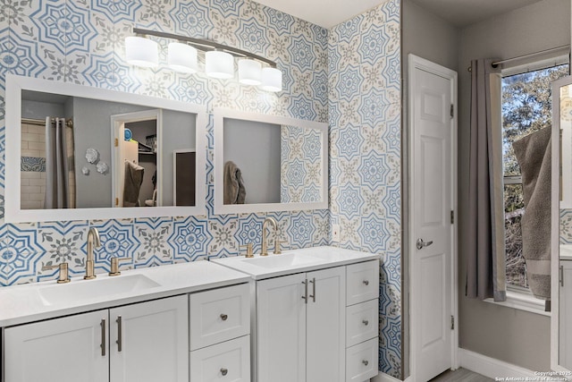 bathroom with a sink, double vanity, and wallpapered walls