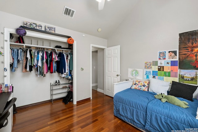 bedroom featuring wood finished floors, visible vents, baseboards, high vaulted ceiling, and a closet