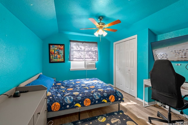 bedroom featuring a ceiling fan, a textured ceiling, wood finished floors, a closet, and cooling unit