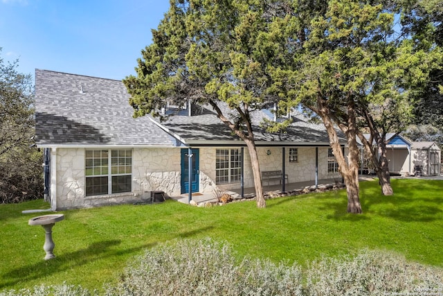 back of property featuring stone siding, a lawn, and roof with shingles