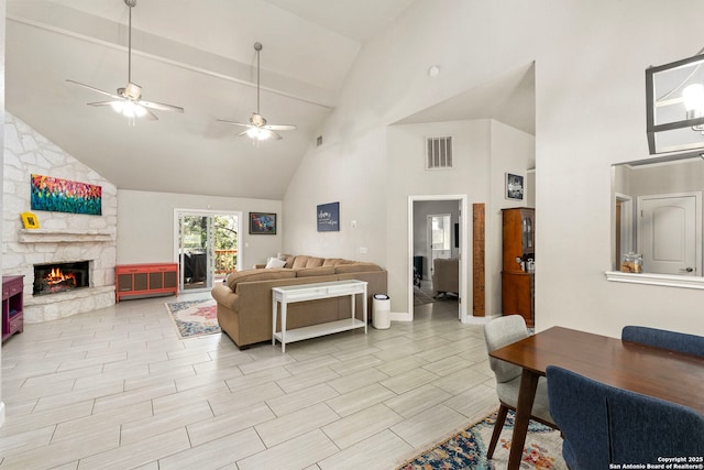 living area with high vaulted ceiling, visible vents, wood tiled floor, and a fireplace