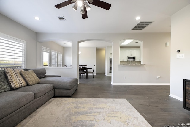 living area featuring visible vents, baseboards, and dark wood finished floors