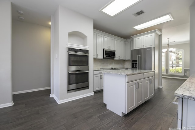 kitchen featuring a kitchen island, dark wood finished floors, white cabinetry, appliances with stainless steel finishes, and decorative backsplash