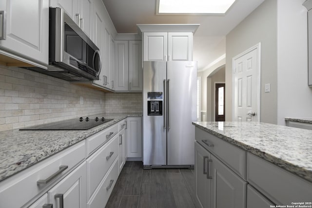 kitchen featuring decorative backsplash, white cabinetry, stainless steel appliances, and wood tiled floor