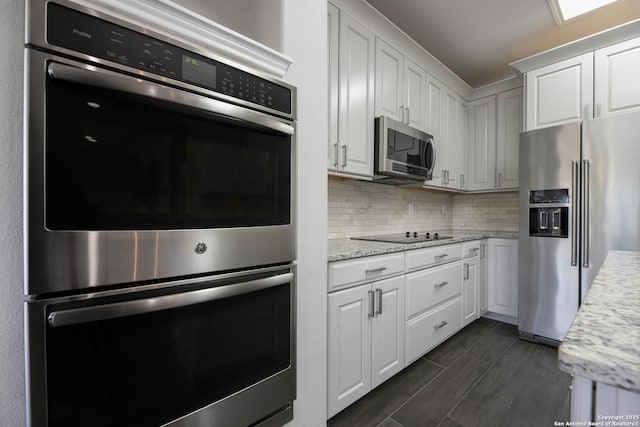 kitchen with decorative backsplash, white cabinets, and appliances with stainless steel finishes