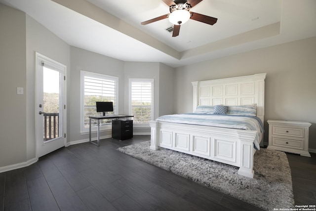 bedroom featuring visible vents, baseboards, a tray ceiling, dark wood-style floors, and a ceiling fan