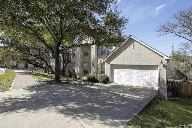 traditional home with a garage, brick siding, driveway, and fence