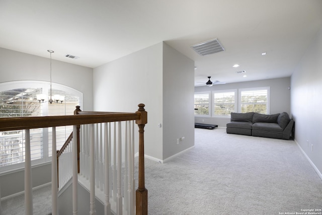 hallway with visible vents, carpet floors, baseboards, a notable chandelier, and an upstairs landing