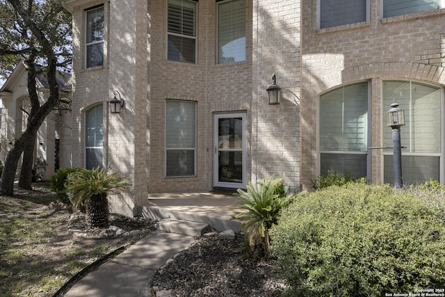 entrance to property featuring brick siding and a patio area