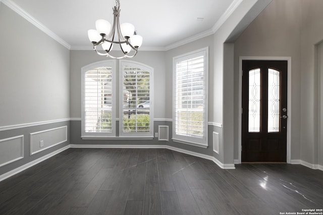 foyer featuring dark wood-style floors, baseboards, wainscoting, crown molding, and a notable chandelier