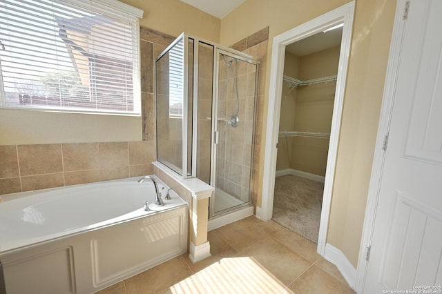 bathroom with tile patterned floors, a walk in closet, a garden tub, and a shower stall