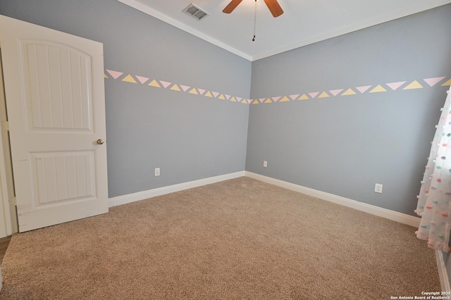 carpeted spare room featuring visible vents, baseboards, ceiling fan, and crown molding