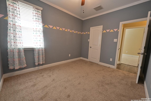 unfurnished bedroom with a ceiling fan, baseboards, visible vents, crown molding, and carpet flooring